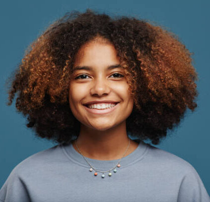Minimal portrait of young African-American woman with natural curly hair looking at camera in studio against blue background